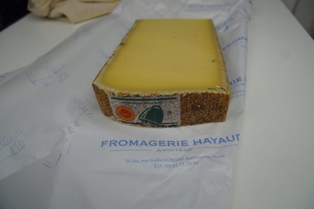 Morceau de Comté Bio posé sur l'emballage de la Fromagerie Hayaud à Asnières sur Seine